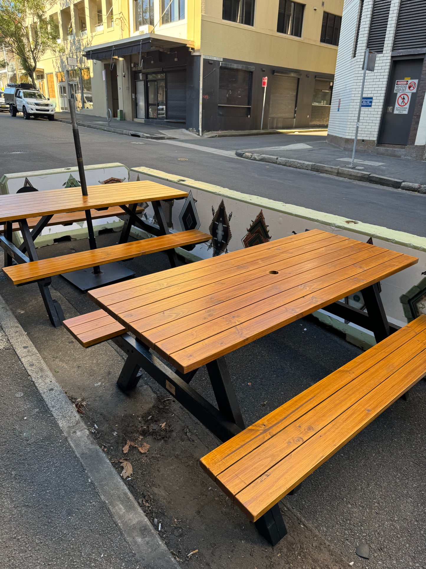 Natural wood picnic table with black frame suited for outdoor café seating in Australia