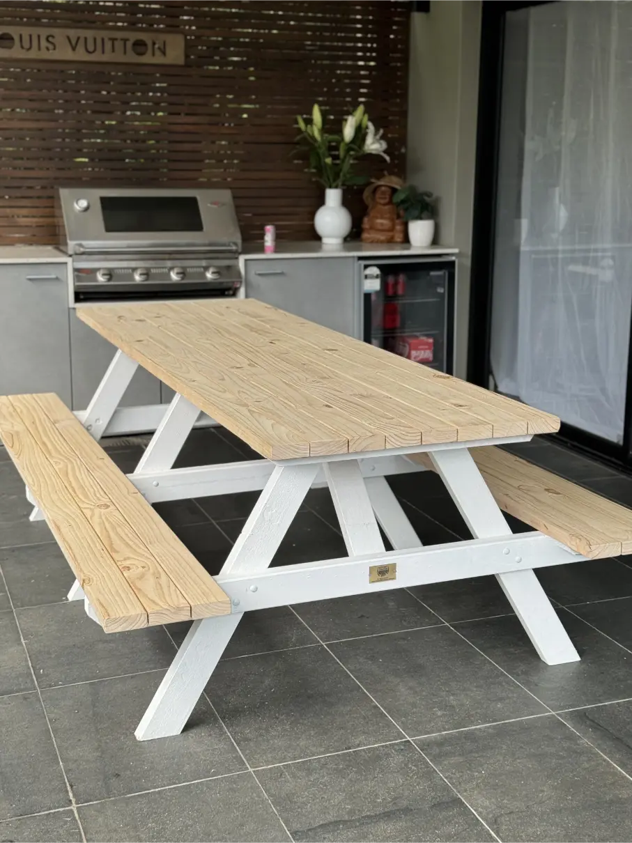 Raw timber picnic table with white legs, ideal for hotel gardens and relaxed guest seating areas in Australia