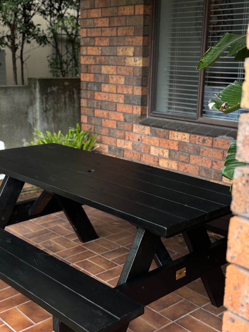 Black heavy duty picnic table with umbrella hole ideal for busy restaurant outdoor dining areas needing shade and durable seating in Australia