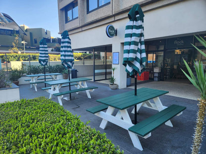 Commercial grade green picnic table with white legs and umbrella hole, designed for shaded restaurant outdoor dining areas with high customer traffic in Australia