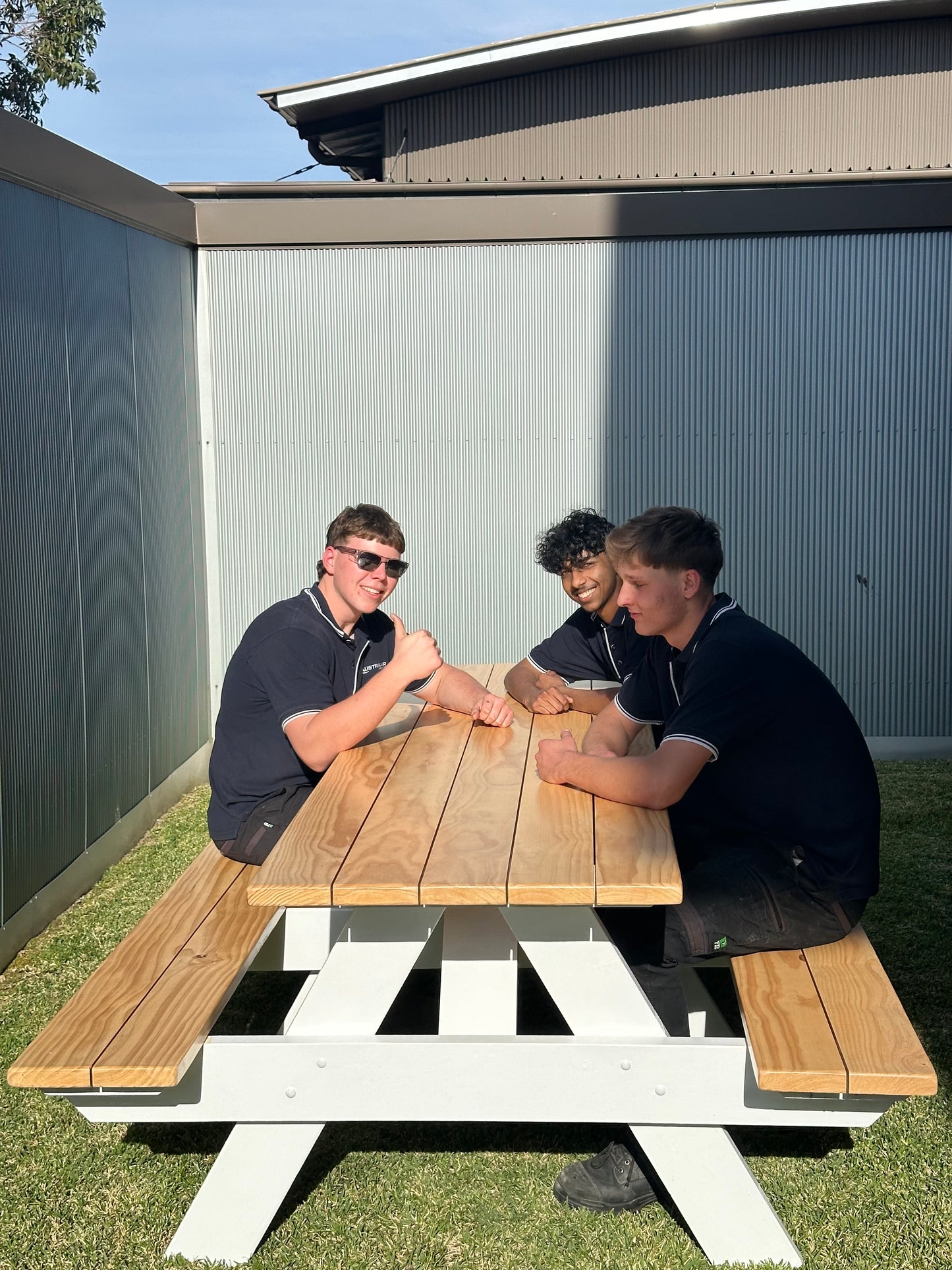 Commercial grade picnic table with white legs and varnished raw timber top, built for busy school yards and durable daily student outdoor use in Australia