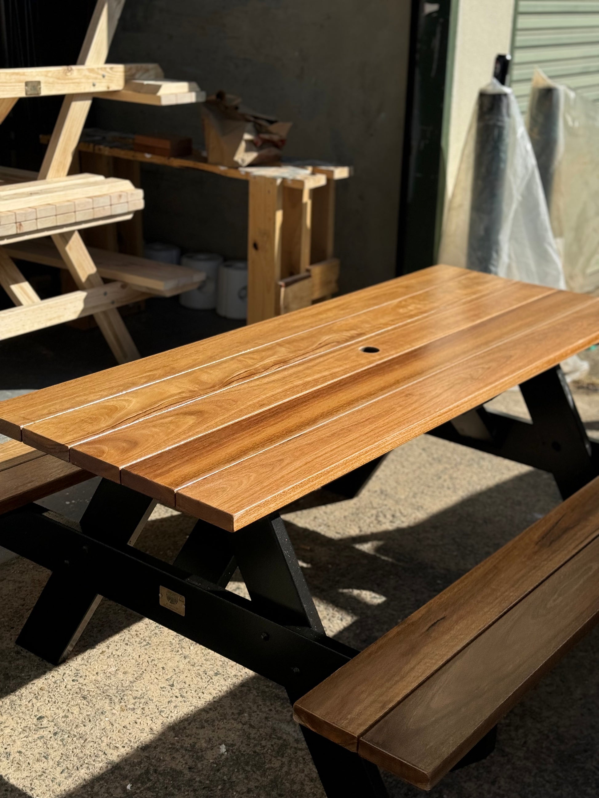Auscraft outdoor hardwood picnic table with a light walnut finish and black legs, perfect for cafés, restaurants, parks and Australian home gardens